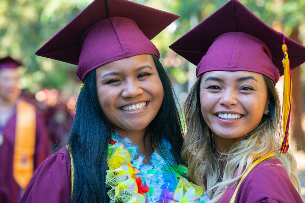 two young women smiling in grad caps